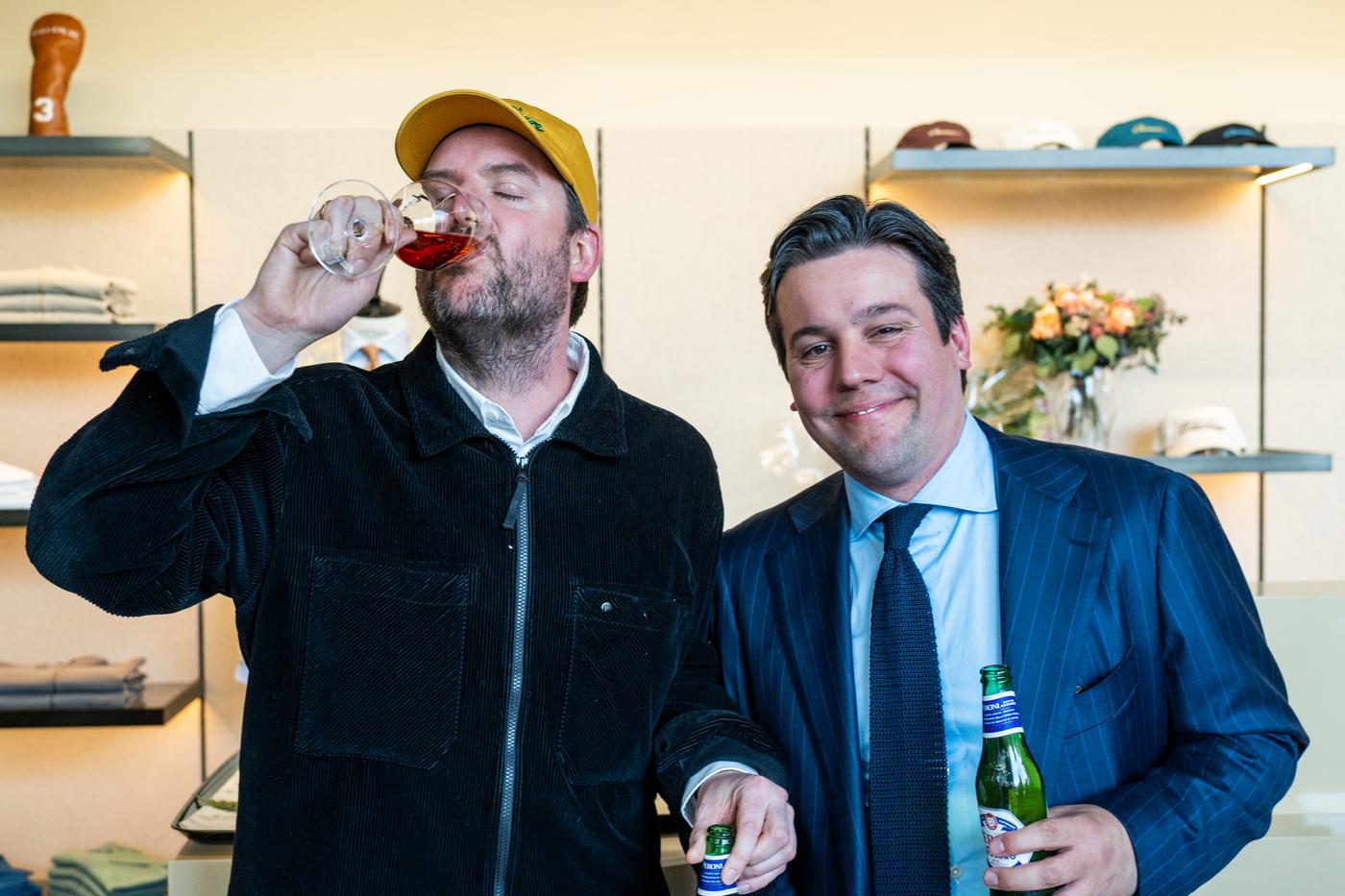 two men are drinking wine and beer in a store .