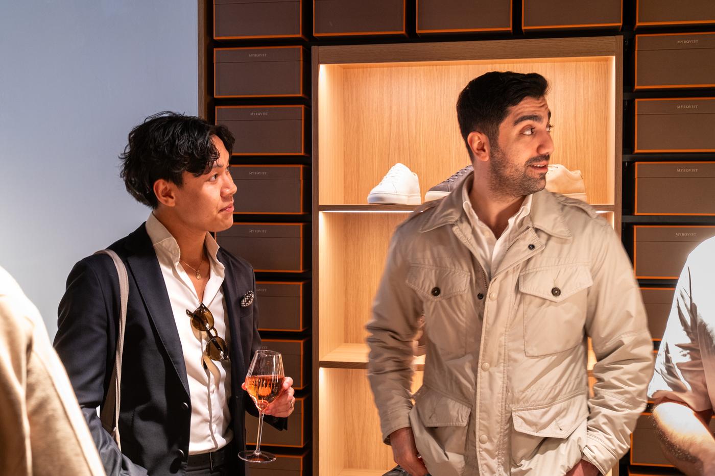 two men are standing next to each other in a store holding wine glasses .