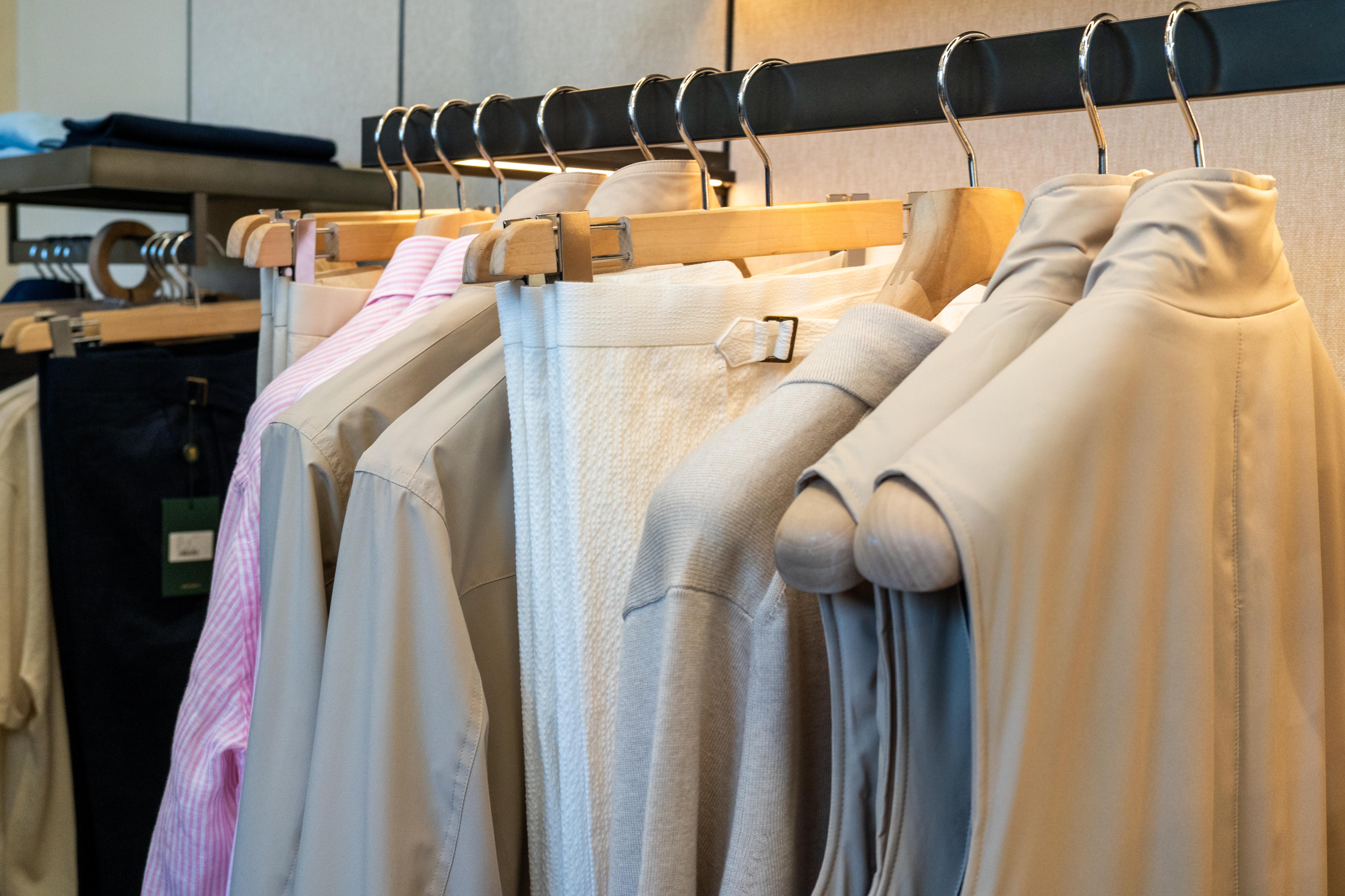 a row of clothes hanging on a rack in a store .