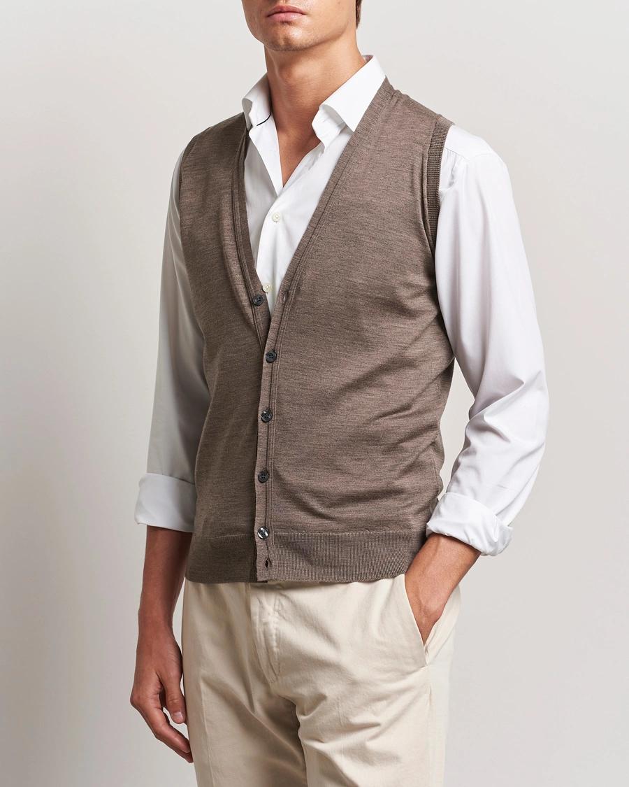 Man wearing a brown button-up vest over a white shirt and light pants.