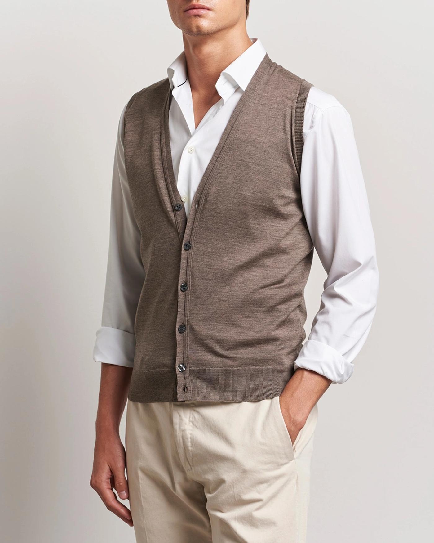 Man wearing a brown button-up vest over a white shirt and light pants.
