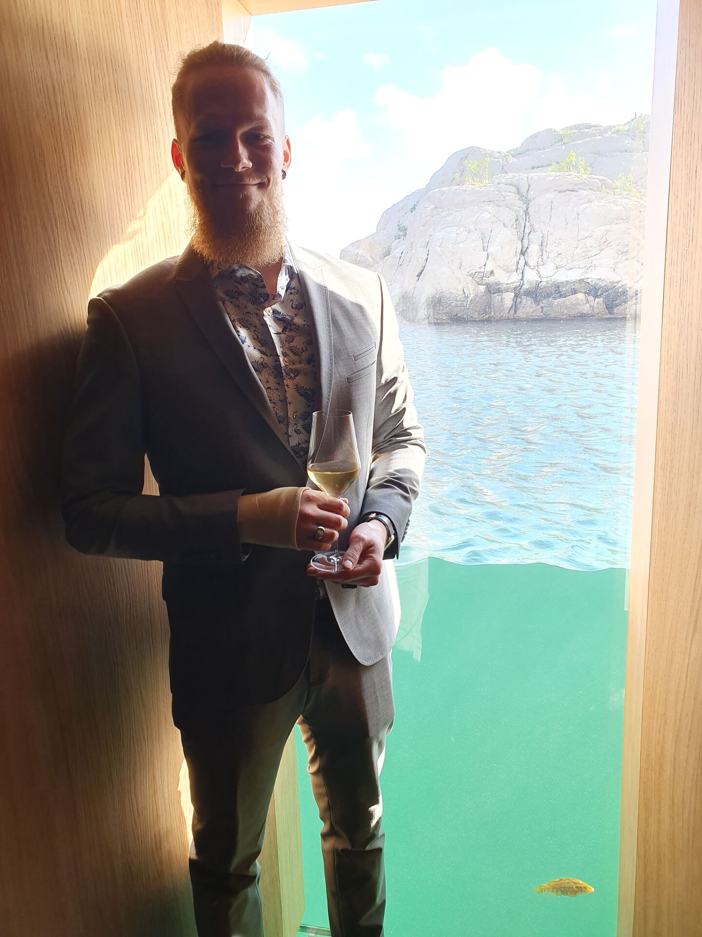 Kristoffer wearing a light gray suit, holding a champagne glass