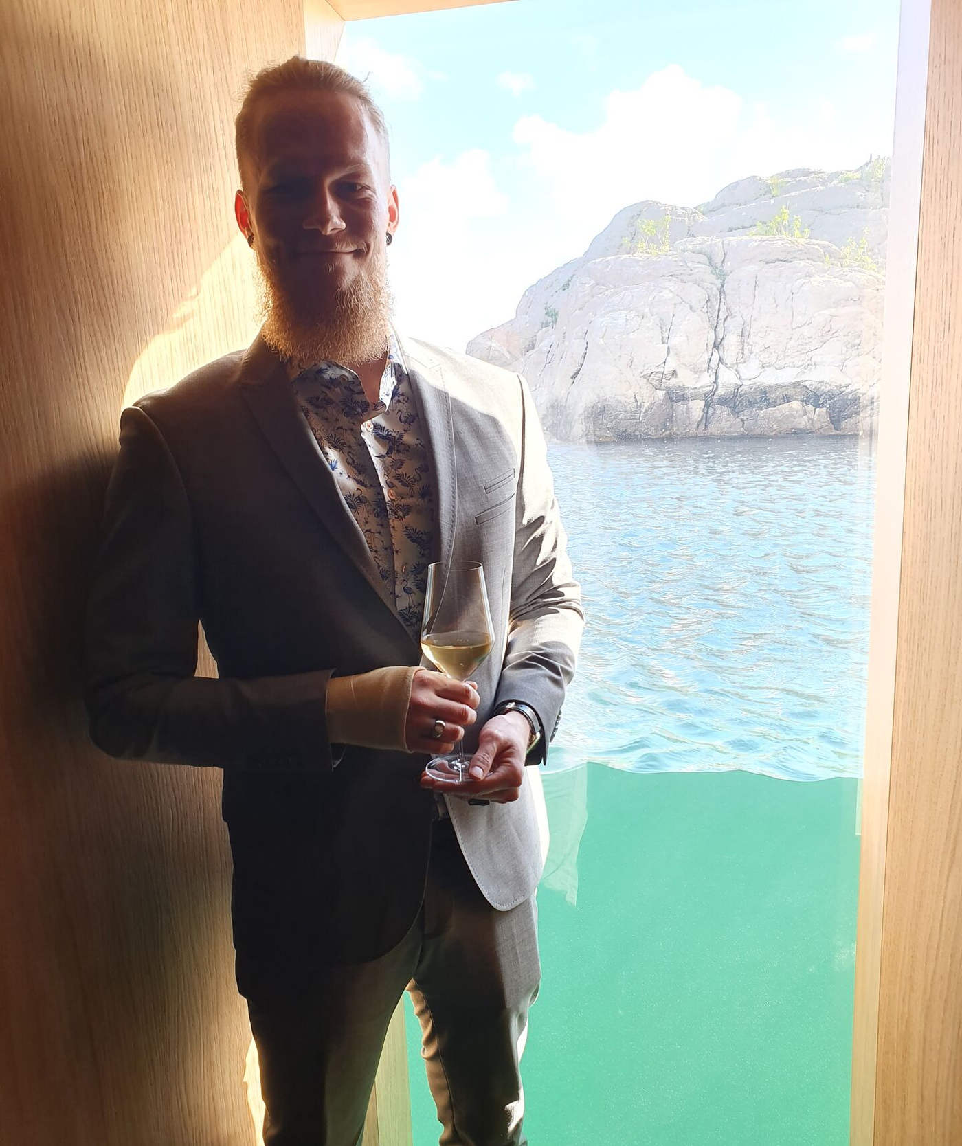 Kristoffer wearing a light gray suit, holding a champagne glass