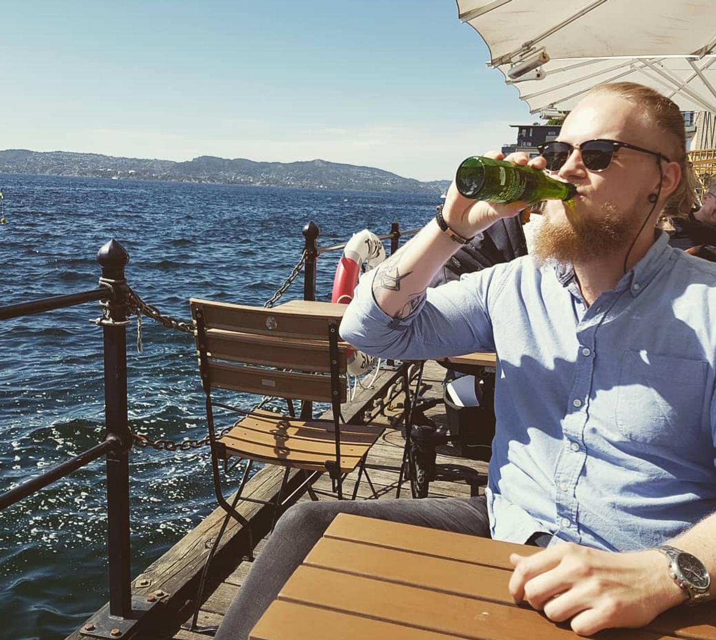 Kristoffer drinking beer in the sun by the water
