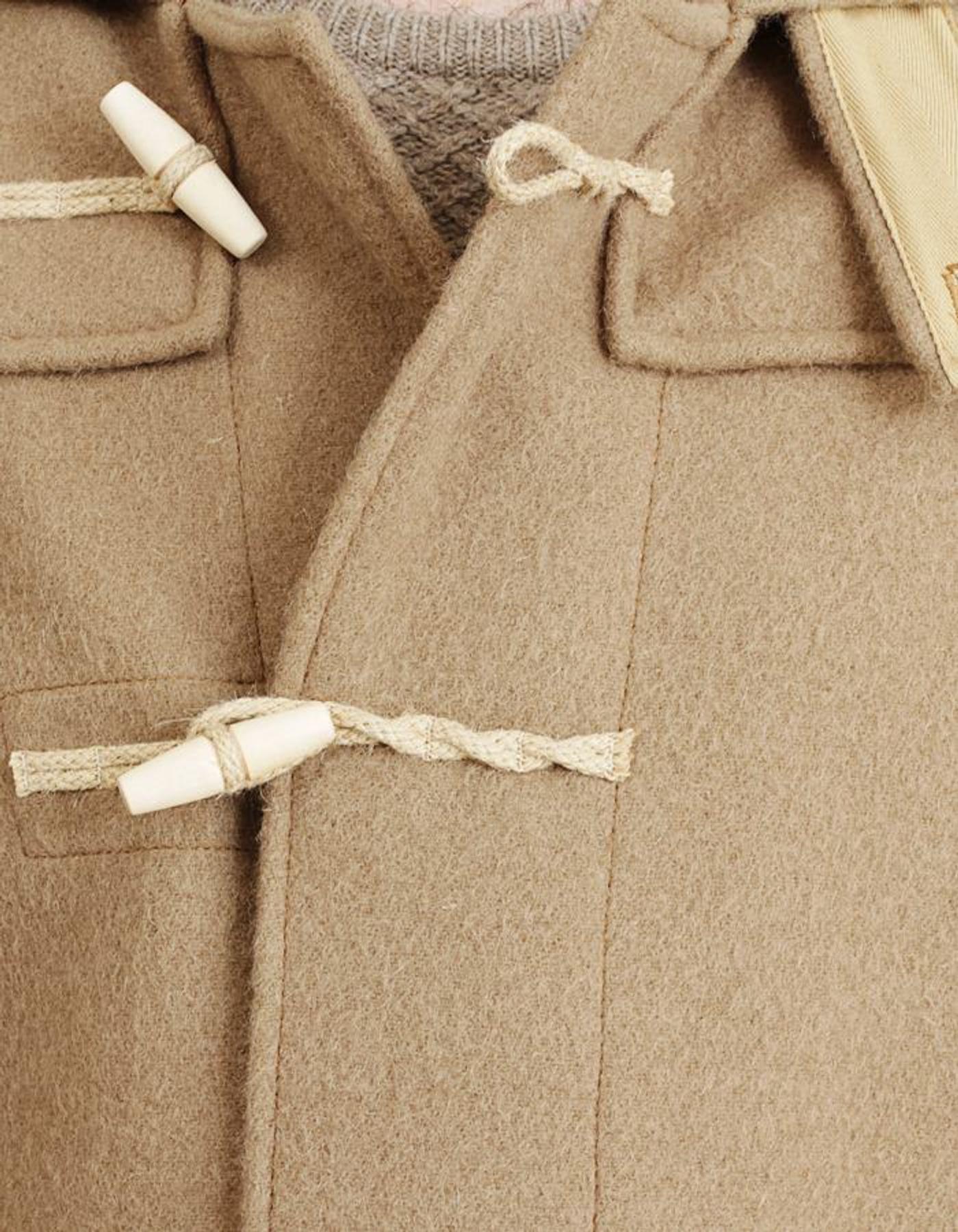 Close-up of a beige duffle coat with white toggle closures and braided loops.
