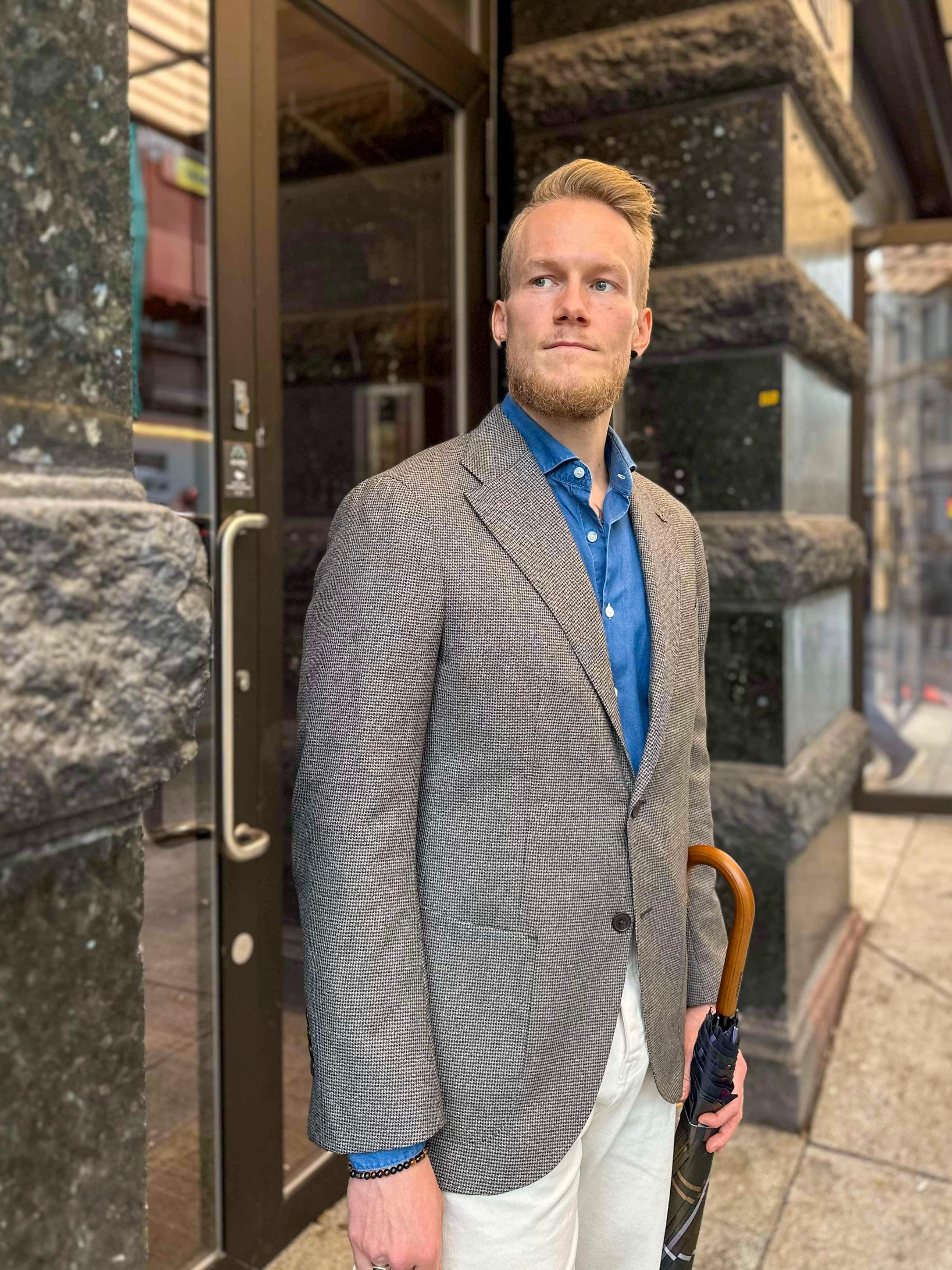 a man in a suit is holding an umbrella in front of a building .