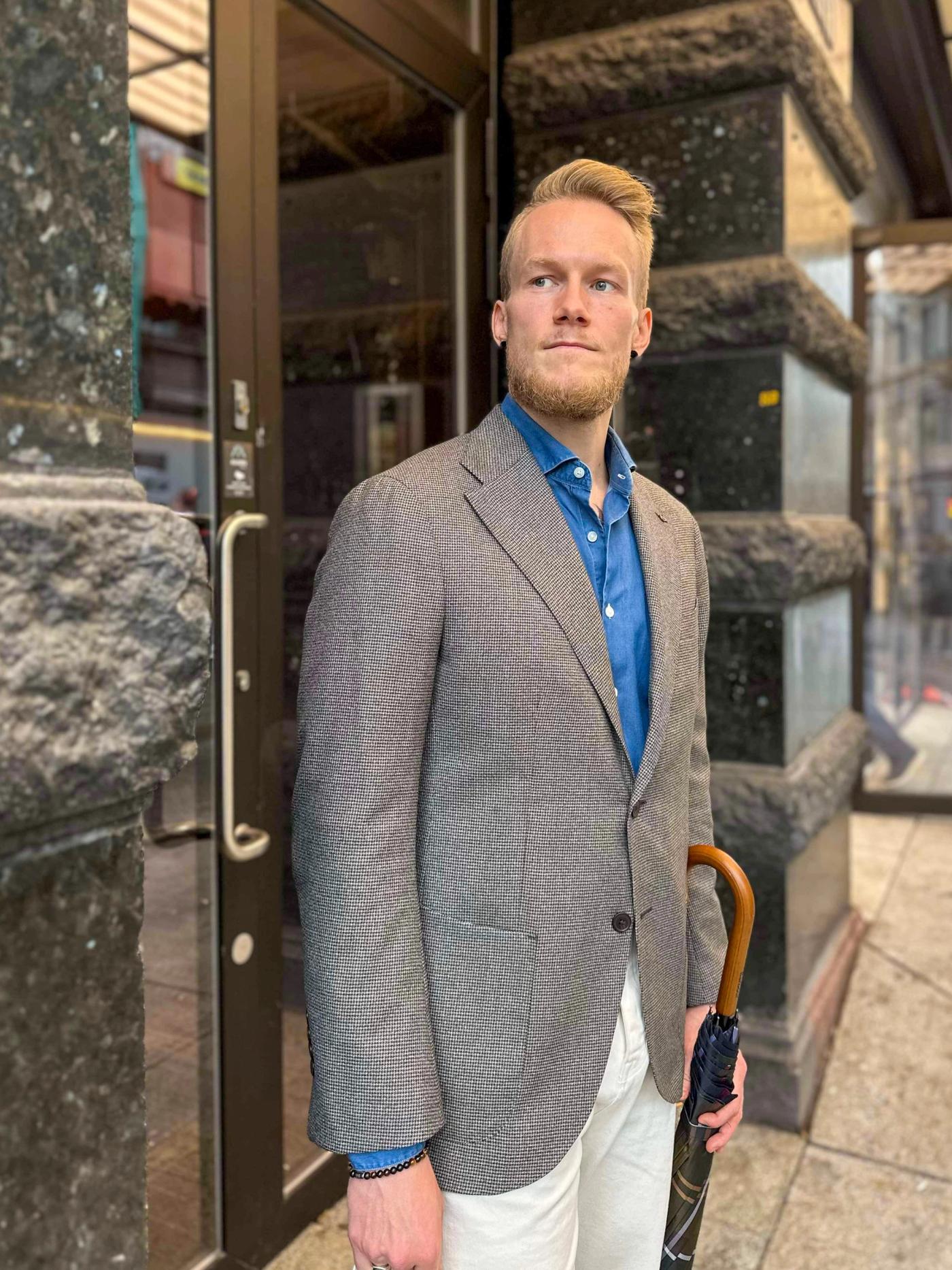 a man in a suit is holding an umbrella in front of a building .
