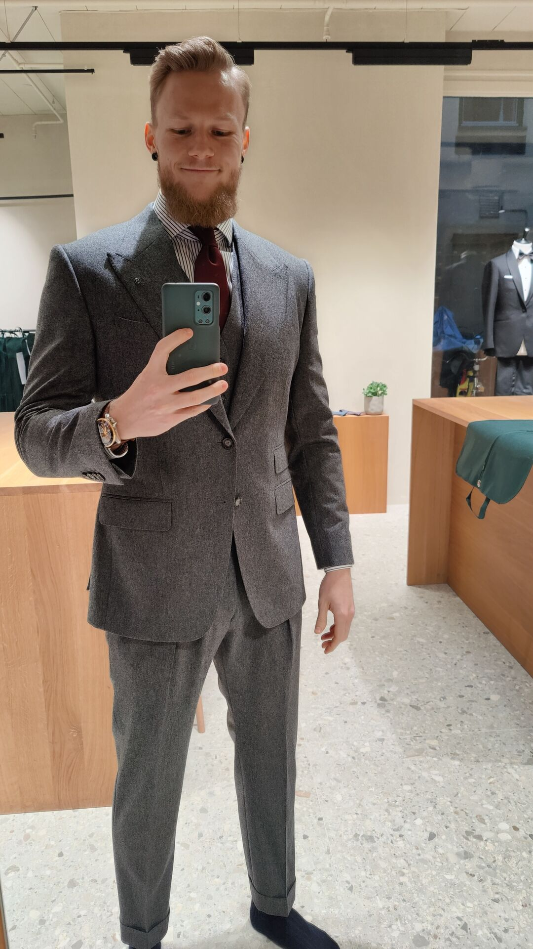 Kristoffer wearing a British looking gray flannel suit inside a tailor store