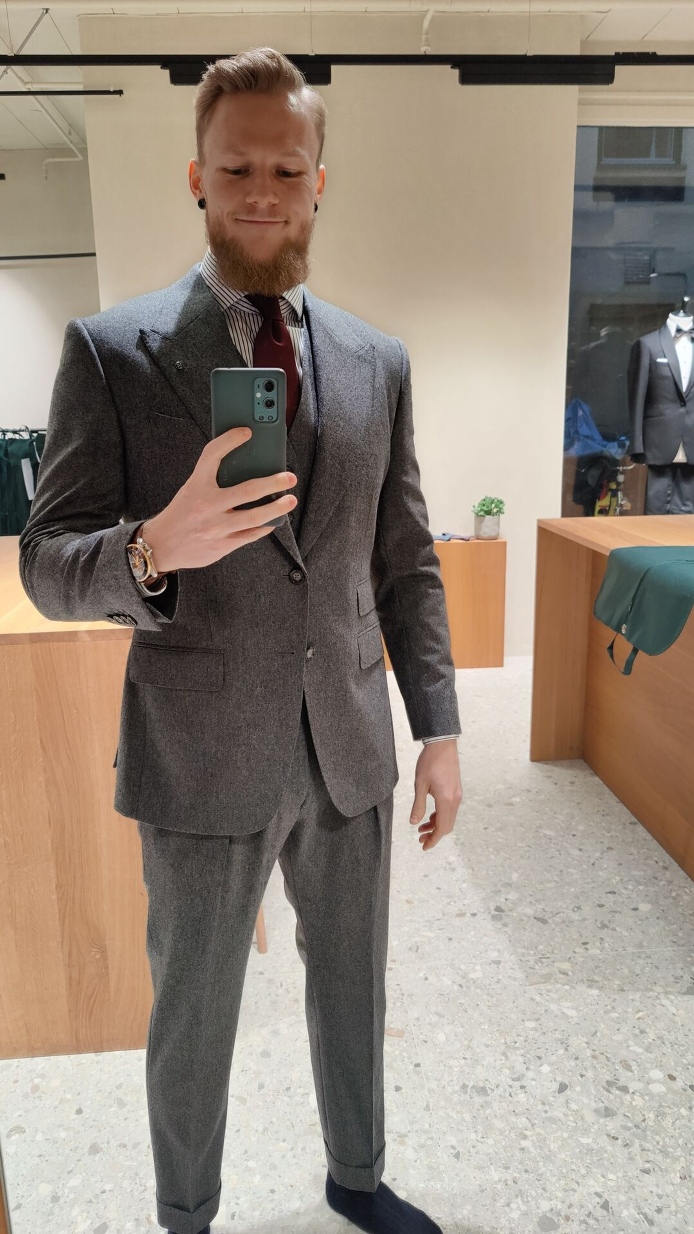 Kristoffer wearing a British looking gray flannel suit inside a tailor store