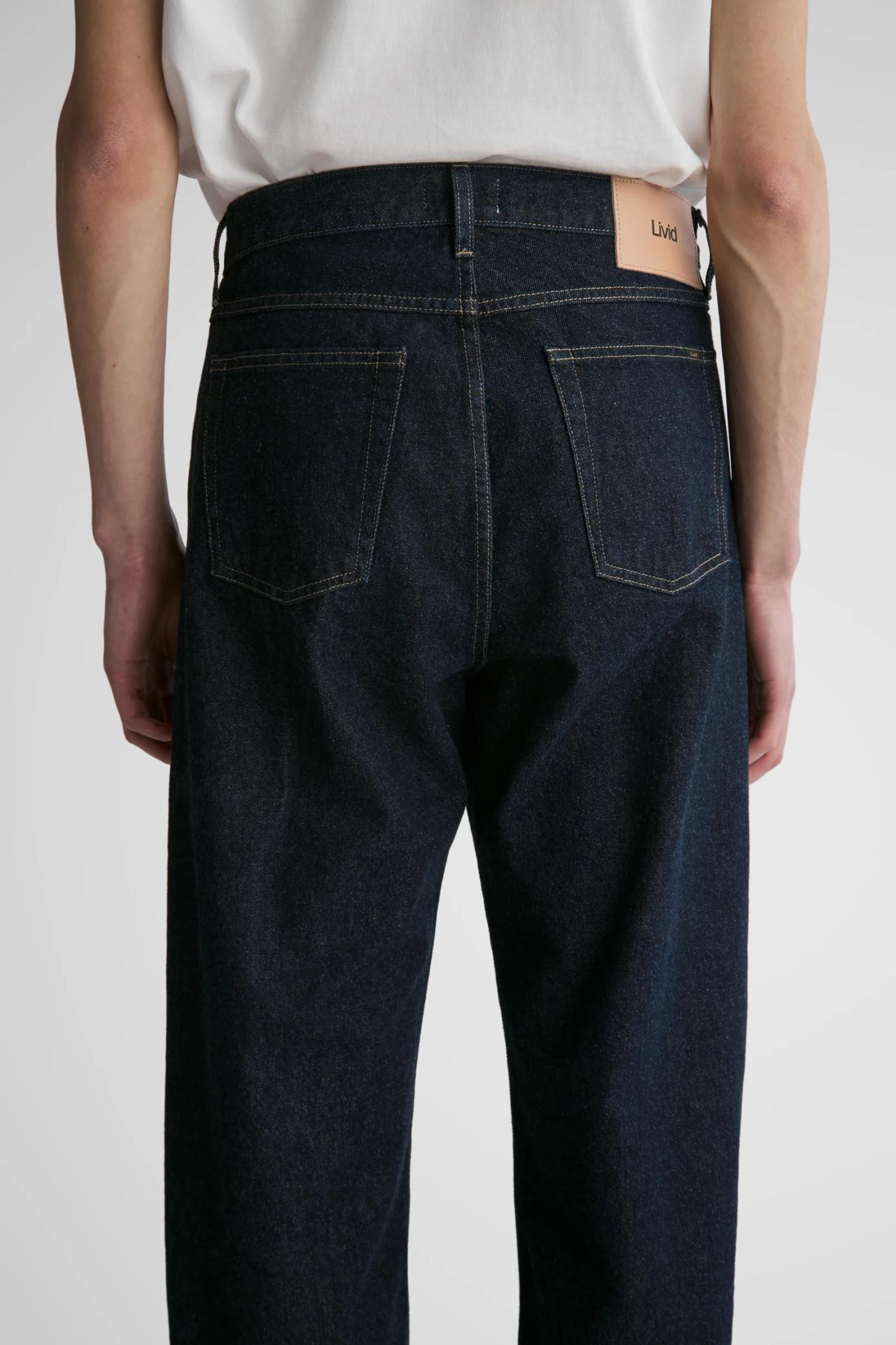 Back view of a person wearing dark indigo jeans with a Livid brand leather patch.