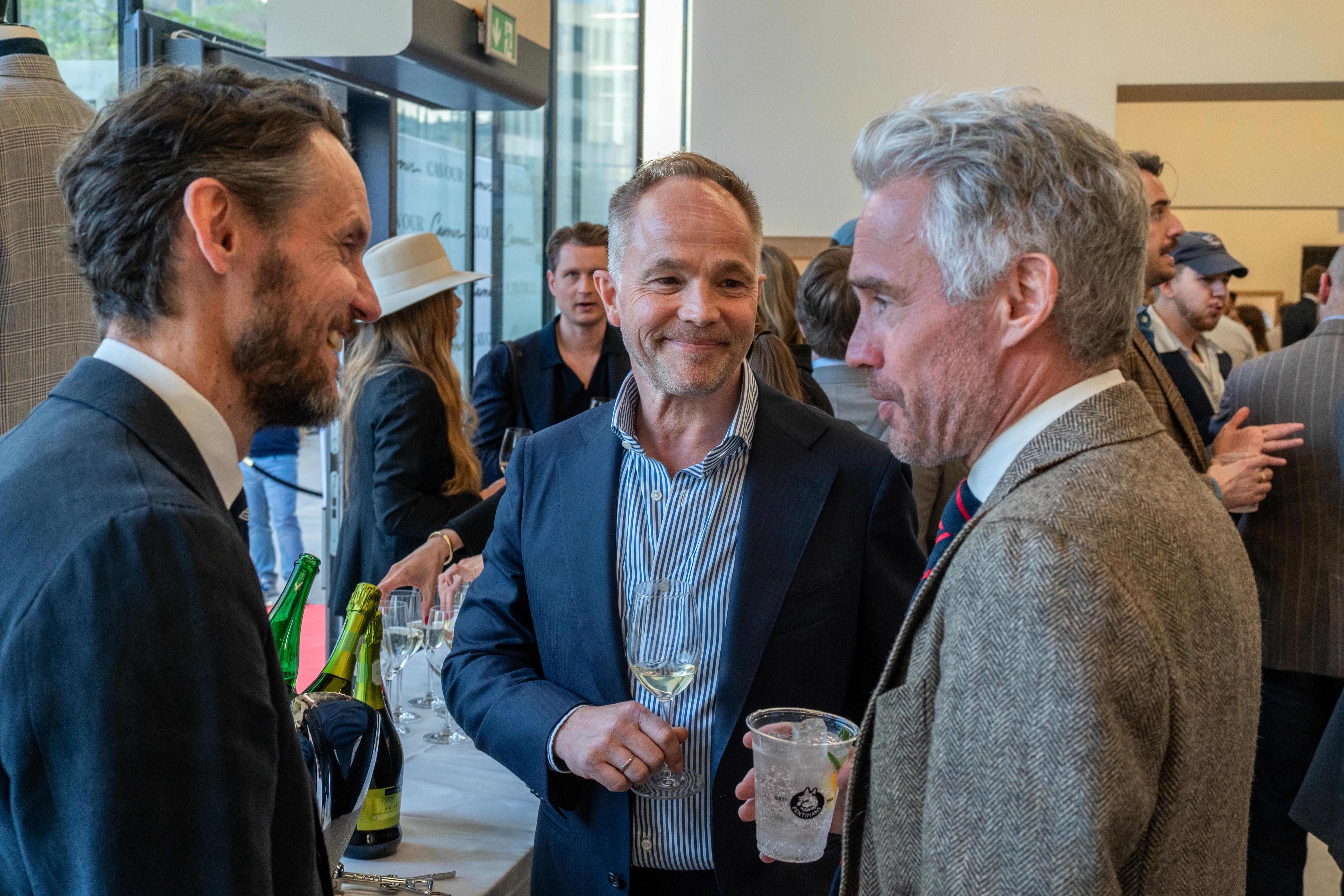 a group of men are standing around a table talking to each other .