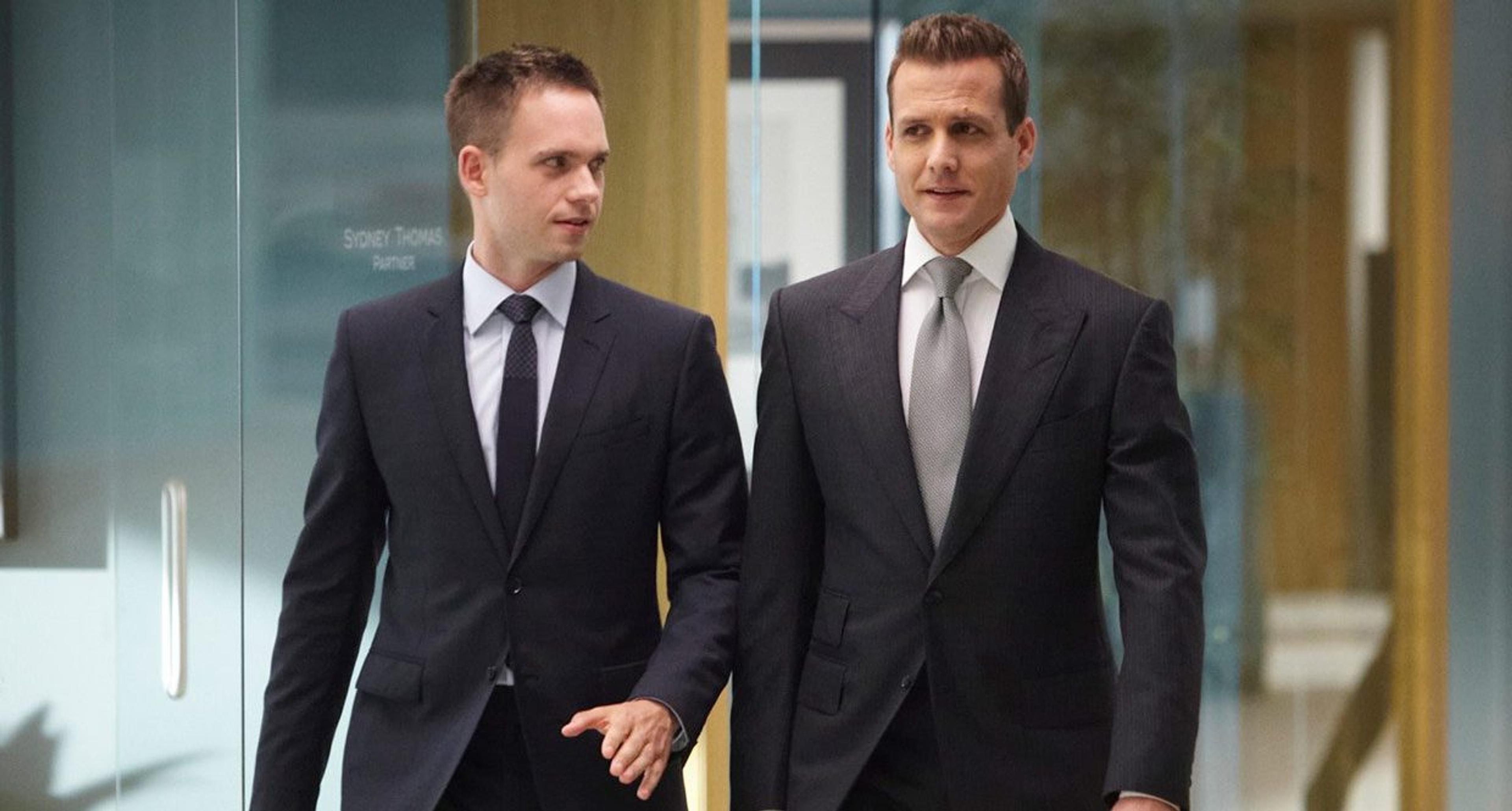 Mike Ross and Harvey Specter in suits walking through a modern office.