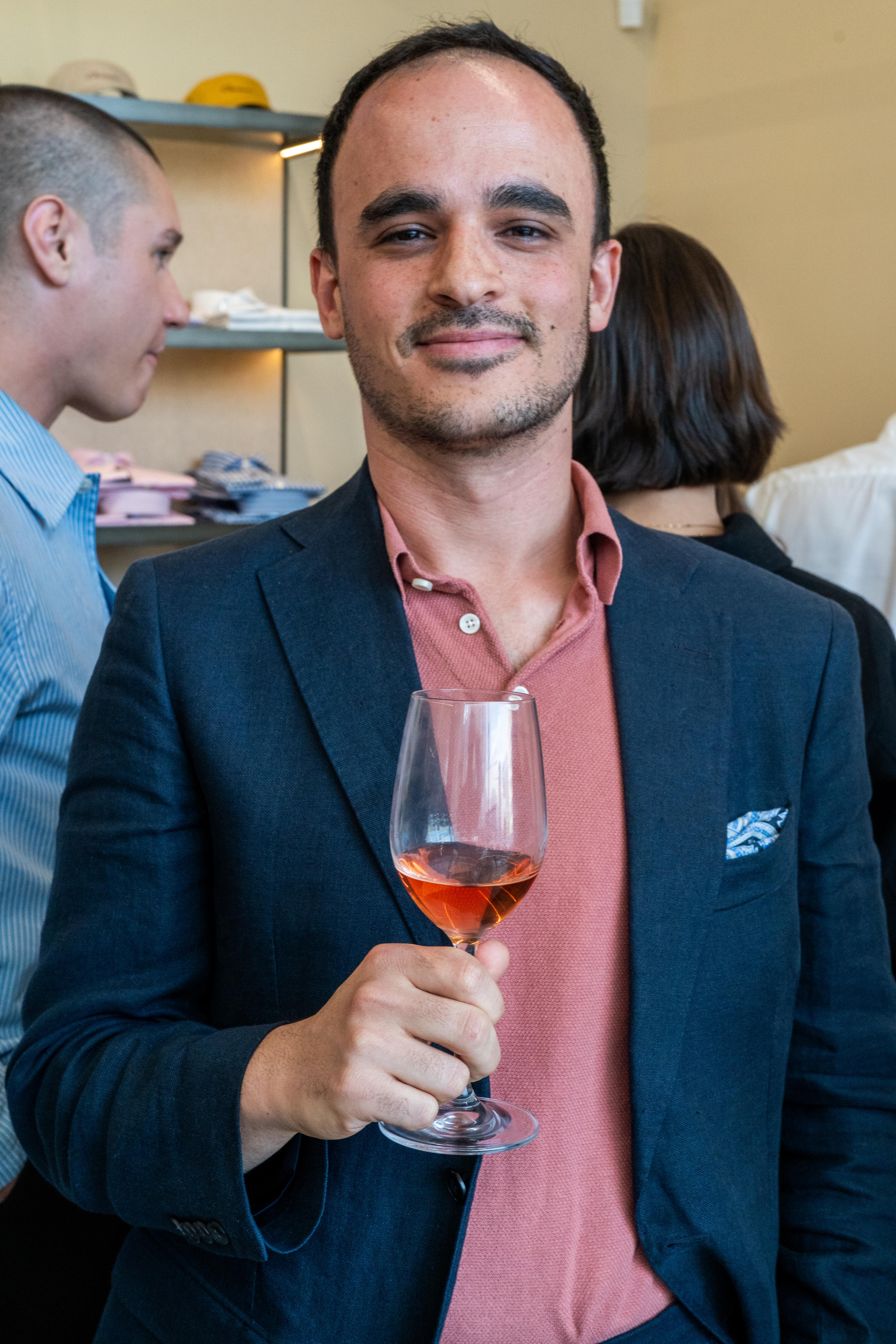 a man in a suit is holding a glass of wine