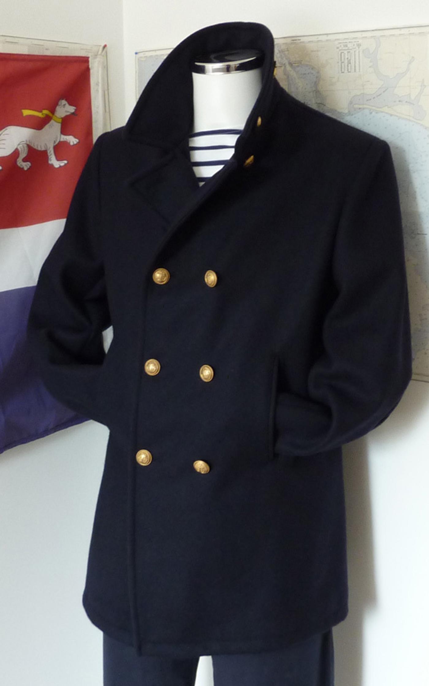 Navy blue double-breasted peacoat with gold buttons on a mannequin over a striped shirt.
