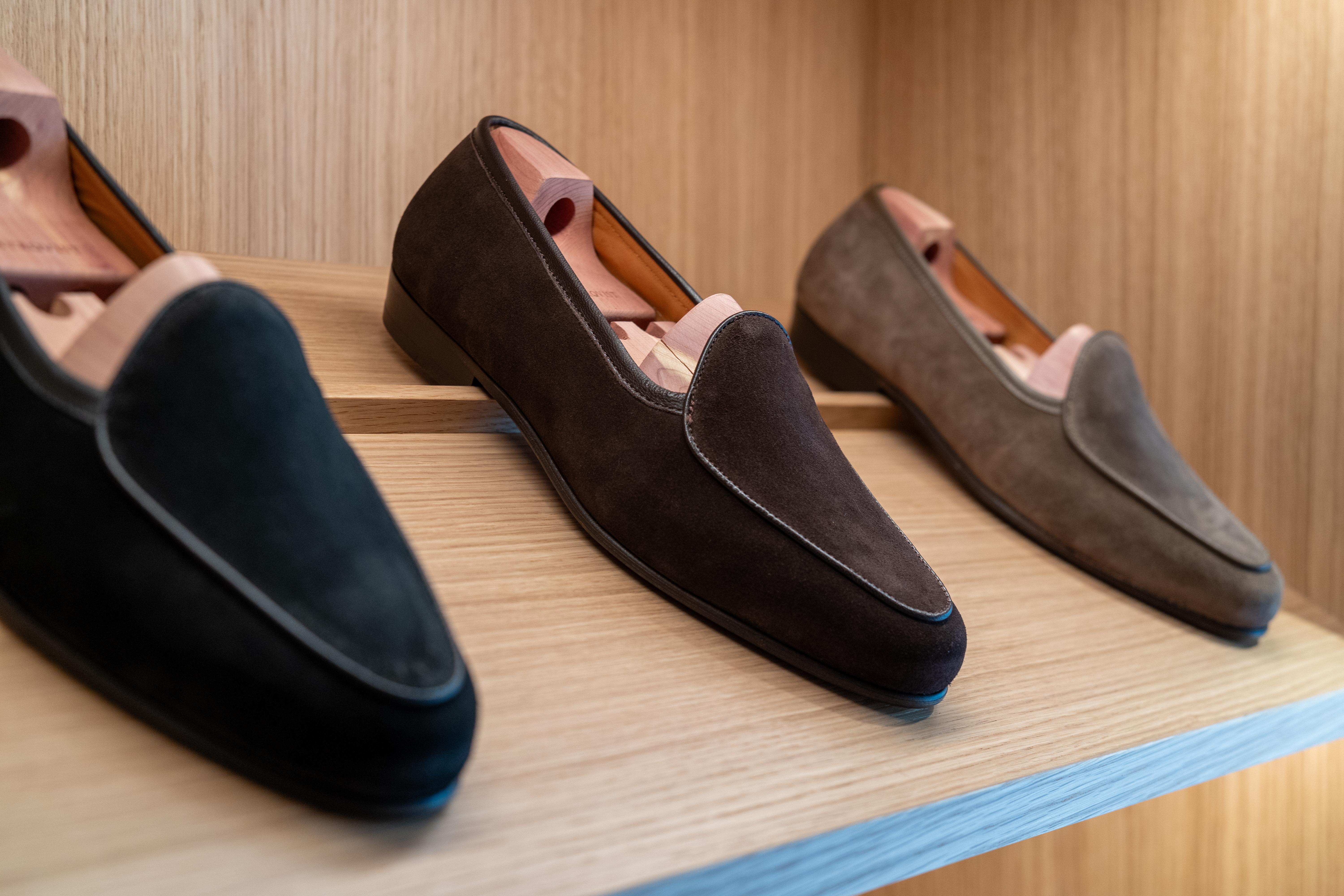 three pairs of loafers are sitting on a wooden shelf .