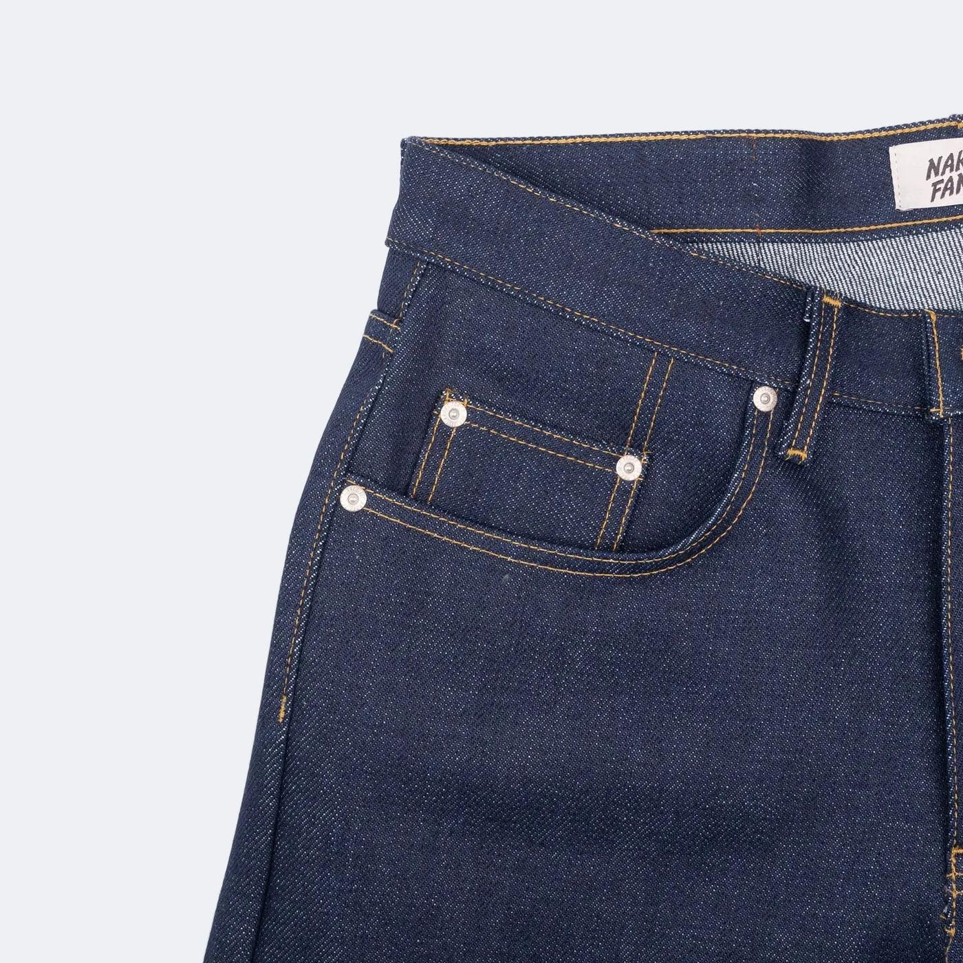 Dark blue denim jeans with front pockets, orange stitching, silver rivets, and a partial brand label.