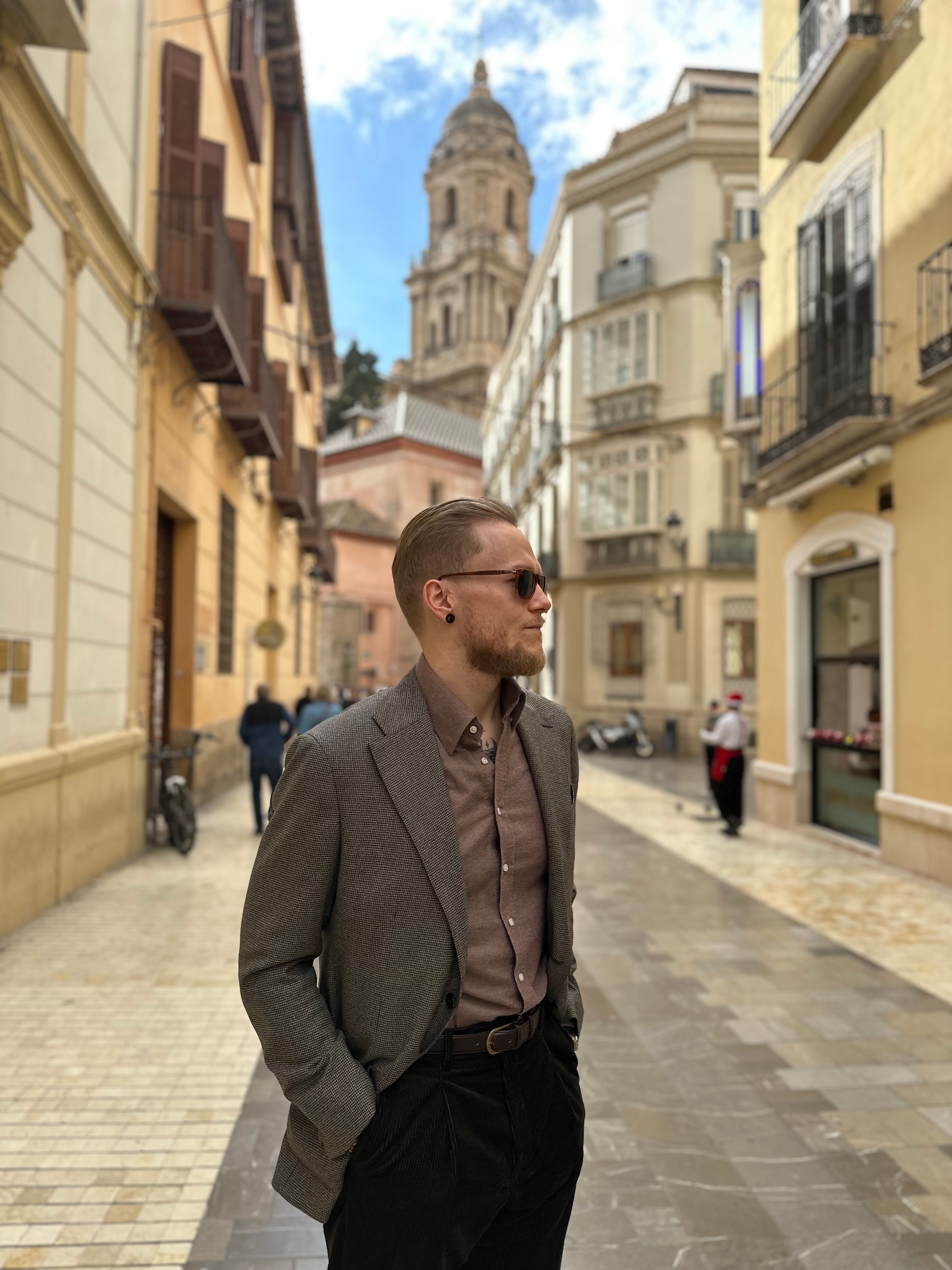 a man in a suit and sunglasses stands on a city street
