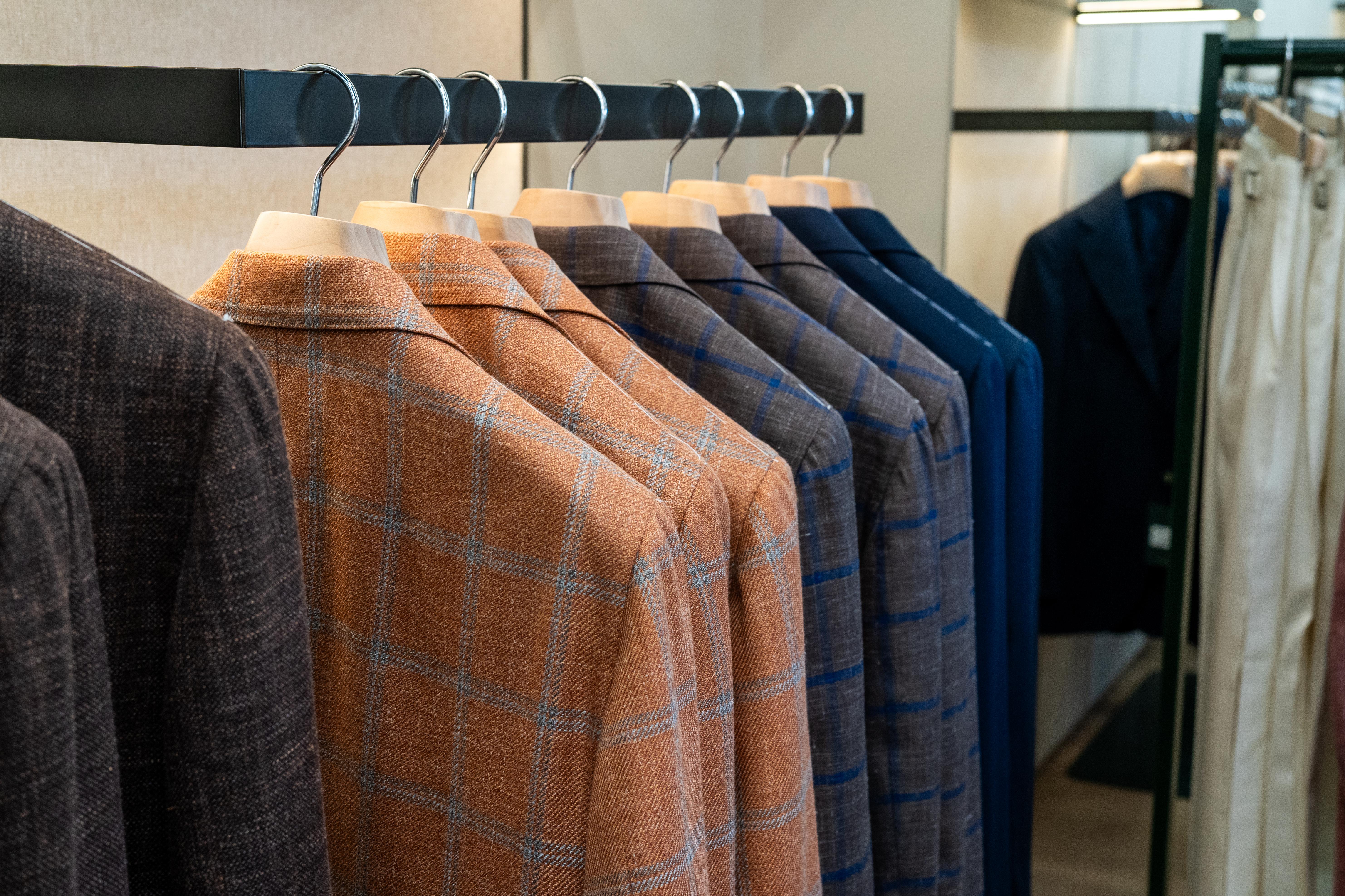 a row of suits hanging on a rack in a store .