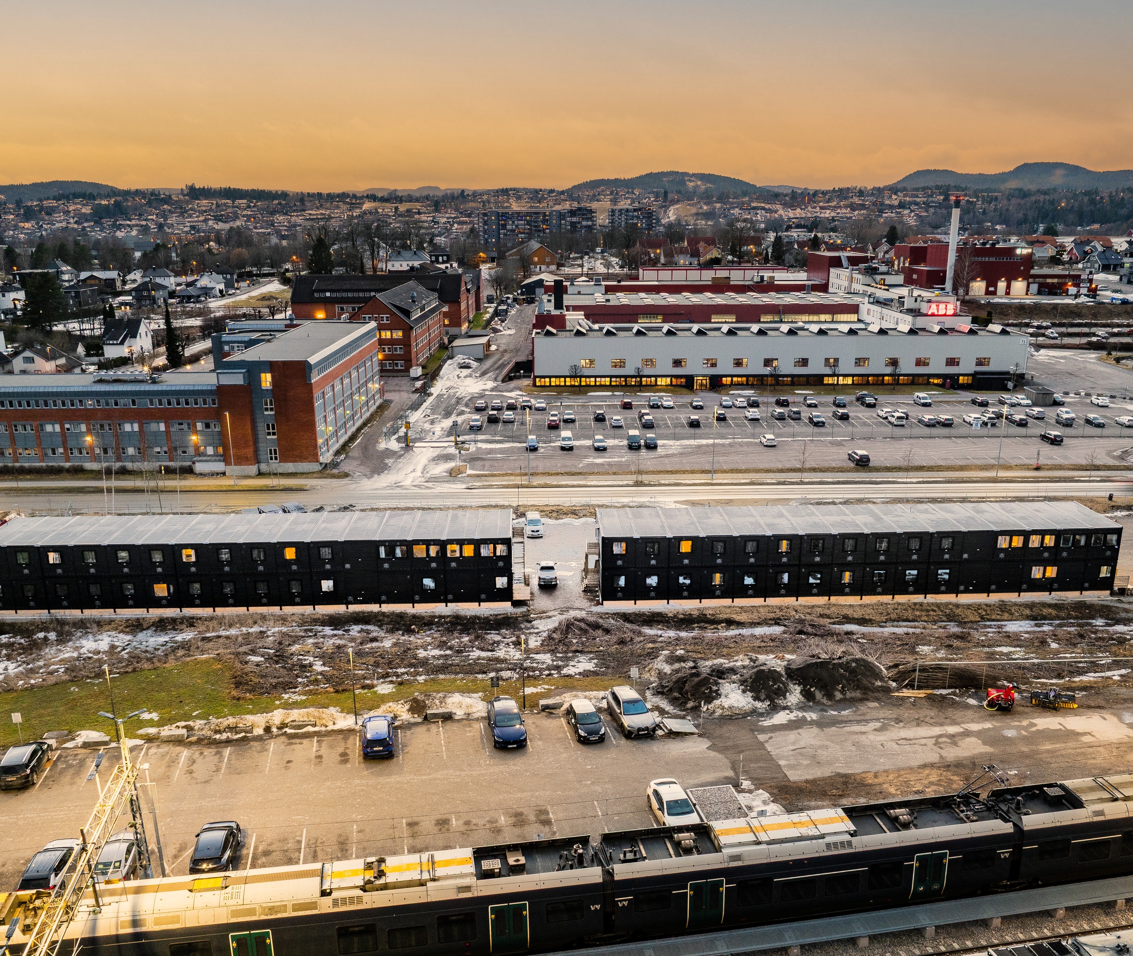 Hotel for workers with a parking lot in front and a city in the background