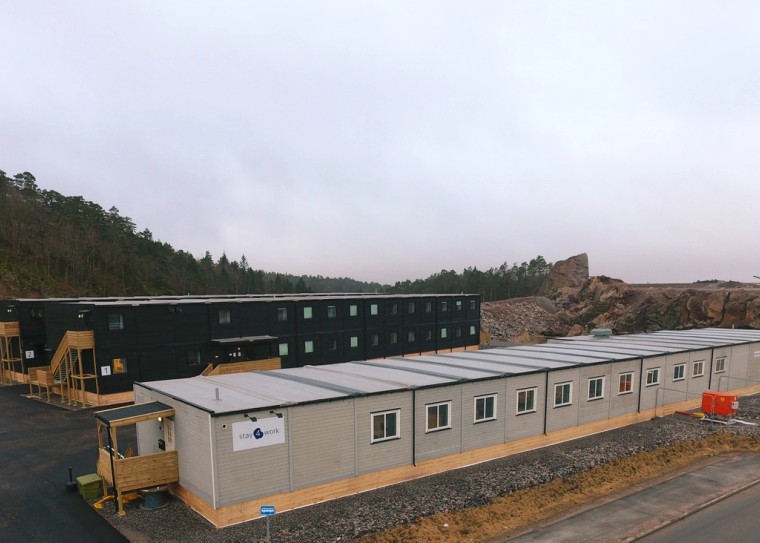 Bygninger på en høyde med skog bak