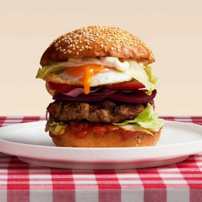 a close up of a hamburger on a plate on a table . a close up of a hamburger on a plate on a table .