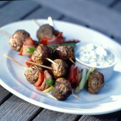 Meatball skewers with vegetables and a side of creamy white dip on a white plate. Meatball skewers with vegetables and a side of creamy white dip on a white plate.