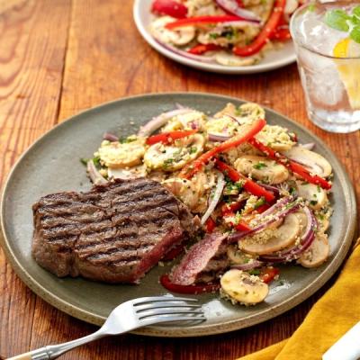 Grilled steak served with a mushroom, red pepper, and couscous salad on a plate. Grilled steak served with a mushroom, red pepper, and couscous salad on a plate.
