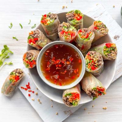 a bowl of spring rolls with dipping sauce on a table a bowl of spring rolls with dipping sauce on a table