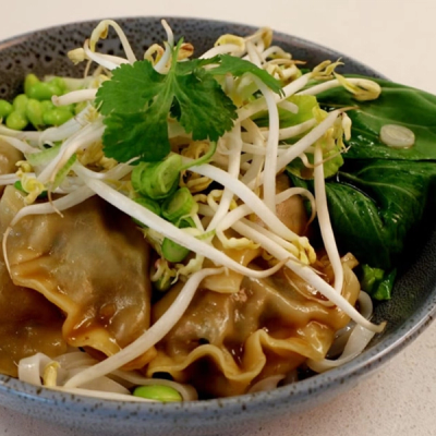 a bowl of noodles with vegetables and sprouts on a table . a bowl of noodles with vegetables and sprouts on a table .