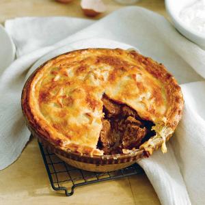 a pie with a slice taken out of it is sitting on a cooling rack.