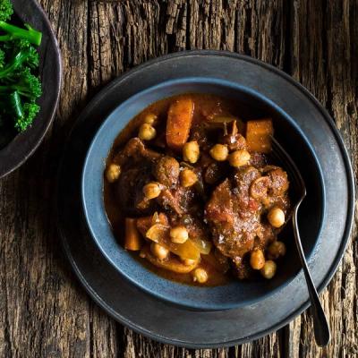 a bowl of stew with chickpeas on a wooden table .