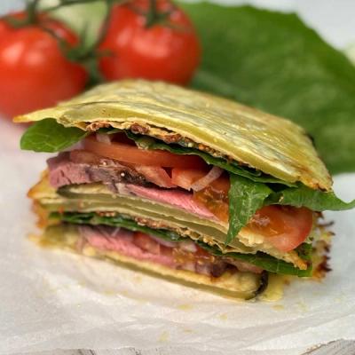 a close up of a sandwich made with pickle bread on a table with tomatoes in the background .