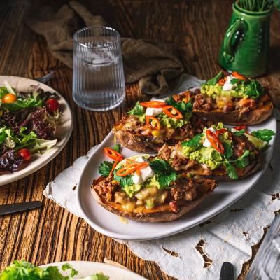 a white plate topped with stuffed sweet potatoes and guacamole on a wooden table .