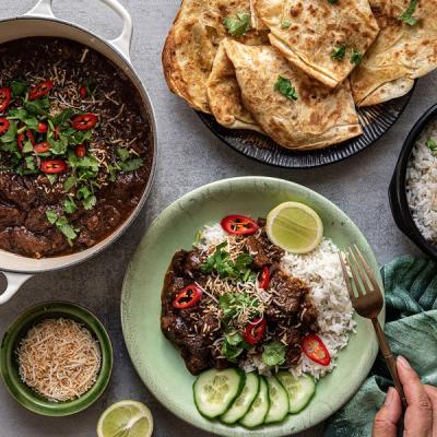 a person is holding a fork over a plate of food on a table . a person is holding a fork over a plate of food on a table .