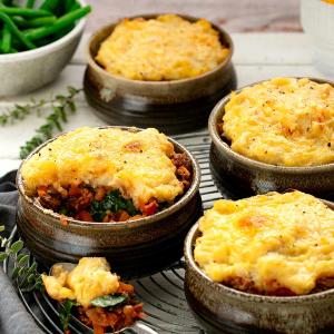 four bowls of beef and lentil pies with golden cauliflower mash on top four bowls of beef and lentil pies with golden cauliflower mash on top