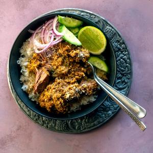 a bowl of food with beef, rice and vegetables on a plate with a fork . a bowl of food with beef, rice and vegetables on a plate with a fork .