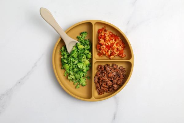 a yellow plate topped with broccoli , pasta , and meat with a wooden spoon . a yellow plate topped with broccoli , pasta , and meat with a wooden spoon .