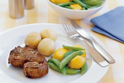 A plate of lamb chops, small potatoes, snap peas, and yellow vegetables.