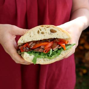 a person is holding a sandwich in their hands .