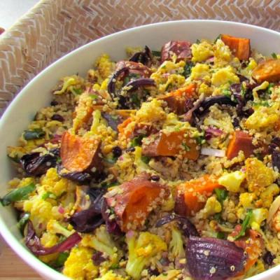a white bowl filled with rice and vegetables is sitting on a wooden table . a white bowl filled with rice and vegetables is sitting on a wooden table .
