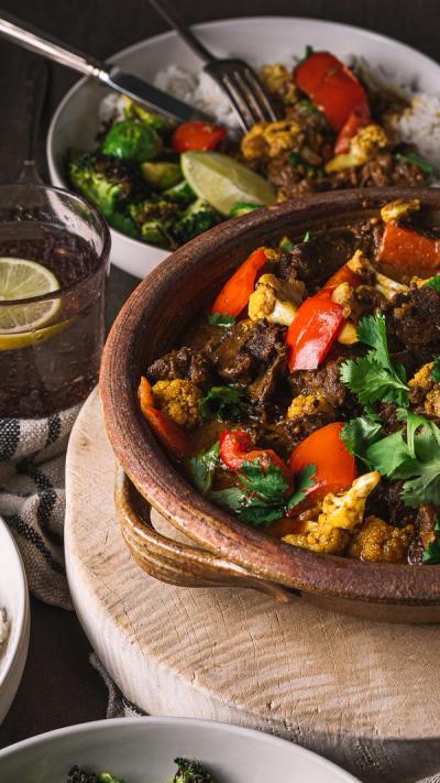 a table topped with bowls of food and a bowl of curry . a table topped with bowls of food and a bowl of curry .