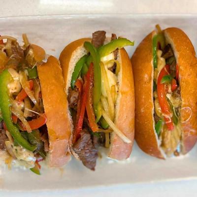 Three sub sandwiches filled with steak, colorful bell peppers, onions, and cheese. Three sub sandwiches filled with steak, colorful bell peppers, onions, and cheese.
