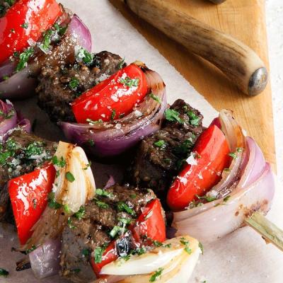 Skewers of grilled meat, red onion, and red capsicum, sprinkled with herbs. Skewers of grilled meat, red onion, and red capsicum, sprinkled with herbs.