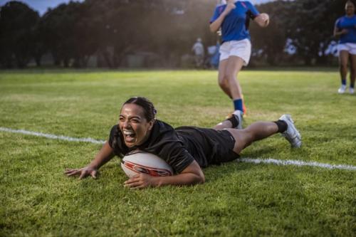a woman is laying on the grass with a rugby ball .