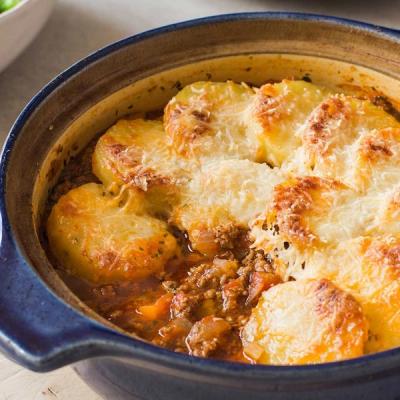Baked meat and potato casserole with melted cheese in a blue dish. Baked meat and potato casserole with melted cheese in a blue dish.