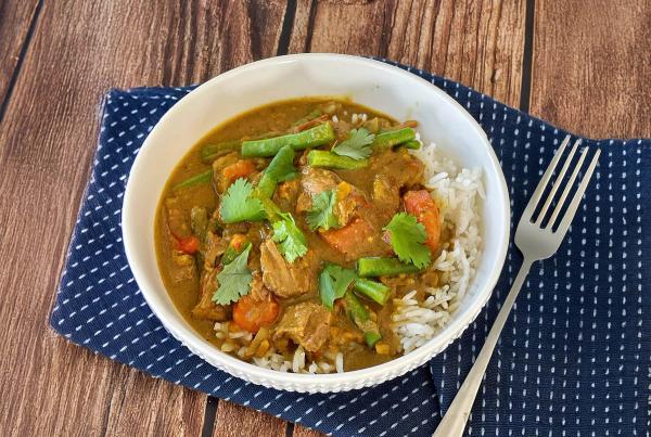 a bowl of food with rice and a fork on a wooden table .