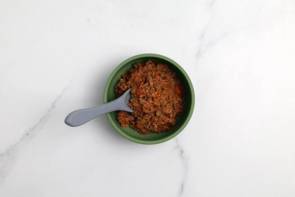 a bowl of food with a spoon in it on a table . a bowl of food with a spoon in it on a table .
