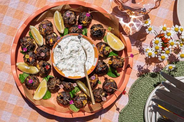 a tray of food with a bowl of tzatziki surrounded by meatballs. a tray of food with a bowl of tzatziki surrounded by meatballs.