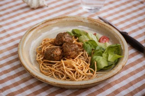 a plate of spaghetti and meatballs with a salad on a table.