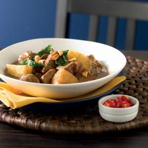 a bowl of stew with meat and potatoes on a table next to a bowl of chili